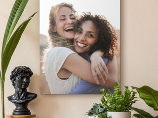 A canvas print of two happy women hugging each other hangs on the wall.