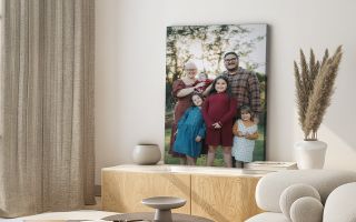modern canvas print of a family sitting on an entertainment system. A natural lit room scene with a sofa and open window concept is visible with small greenery