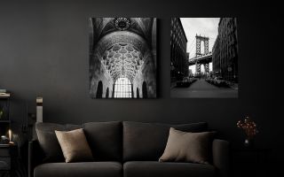 2 canvas prints hanging above a couch in a dark, gloomy, modern room.