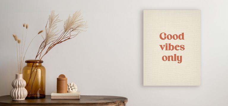 Wall art saying Good vibes only beside vases and decor