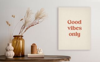 Wall art saying Good vibes only beside vases and decor