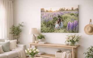A canvas print of a woman and child sitting in a field of purple flowers. Hanging over a shelf in a white room scene with flower accents.