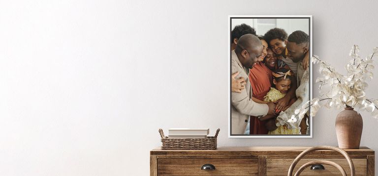 A canvas print of a happy big family hugging each other hangs on the wall.