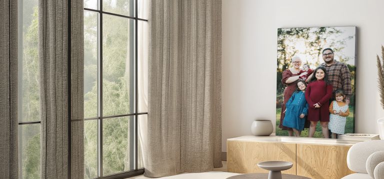 modern canvas print of a family sitting on an entertainment system. A natural lit room scene with a sofa and open window concept is visible with small greenery
