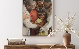 A canvas print of a happy big family hugging each other hangs on the wall.