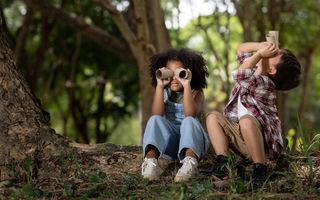 A picture of two children playing pretending they are looking through binoculars