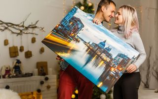 A happy couple looking at each other holding a landscape canvas print.