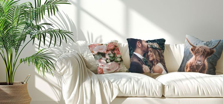 A white couch with some pillows, focusing on one personalized with a couple on their wedding day.