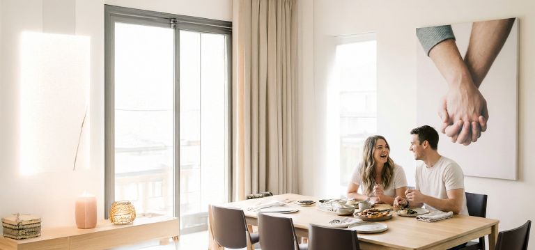 A couple sitting at a table with a canvas print of them holding hands on the wall behind them.
