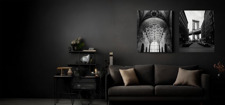 2 canvas prints hanging above a couch in a dark, gloomy, modern room.