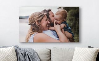 A canvas print of a happy family hanging above a couch.