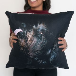 A happy woman holding a personalized pillow with a picture of a dog.
