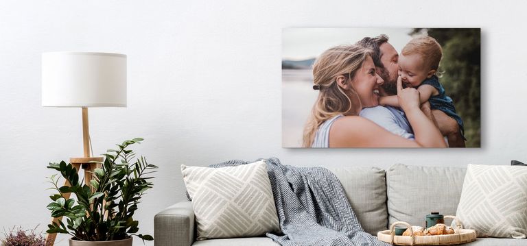 A canvas print of a happy family hanging above a couch.