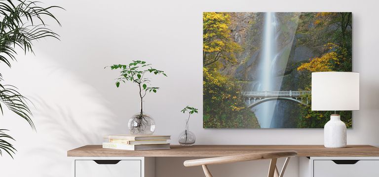 A metal canvas print of a landscape hanging above a desk.