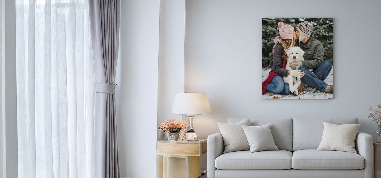 canvas print of a couple and their dog in a wintery scene. Hanging on a wall above a light, modern living room scene